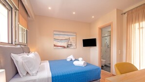 Habitación de hotel con cama, escritorio, silla, televisor y un cuadro en la pared.