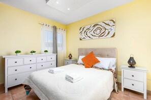 Ein Schlafzimmer mit Bett, weißem Schminktisch, Nachttischen und einem Bild an der Wand.