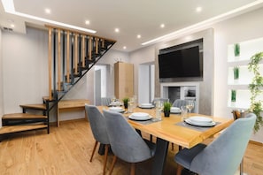 Ein moderner Essbereich mit einem Holztisch, grauen Stühlen und einer Treppe mit Holz- und schwarzen Geländern.