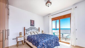 A bedroom with a bed, a nightstand, a lamp, a picture of the Eiffel Tower, and a balcony with a view of the sea. - Villa Kiotari by Villa Plus (Kiotari)