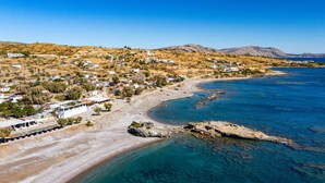A coastal town with white buildings, a sandy beach, and clear blue waters. - Villa Kiotari by Villa Plus (Kiotari)