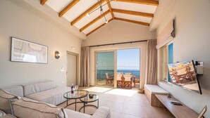 Een moderne woonkamer met een bank, een glazen salontafel en een balkon met uitzicht op zee.