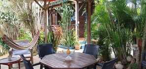 Un espacio al aire libre con mesa de madera, sillas y una hamaca.