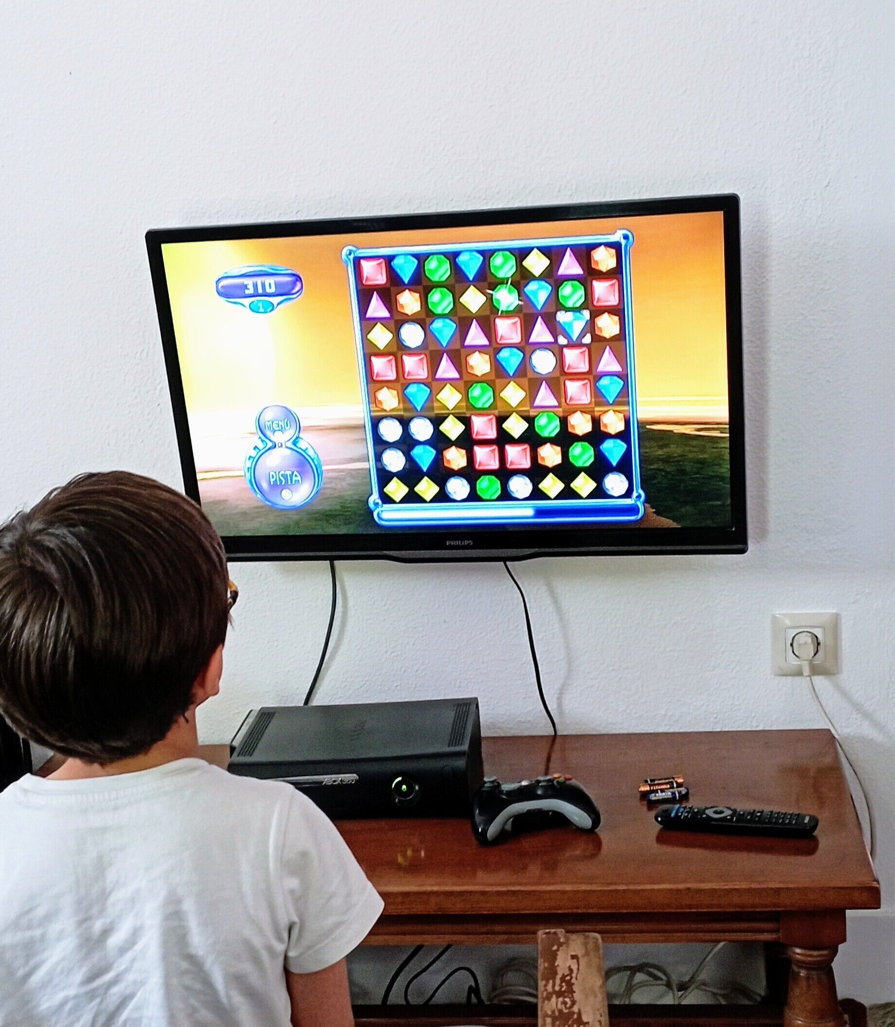 A person playing a match-three puzzle game on a television mounted on a wall.