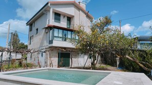 A two-story house with a swimming pool in the foreground.