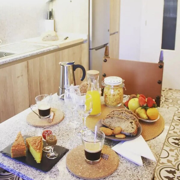A breakfast table with various food items and drinks, including toast, jam, and a fruit bowl.