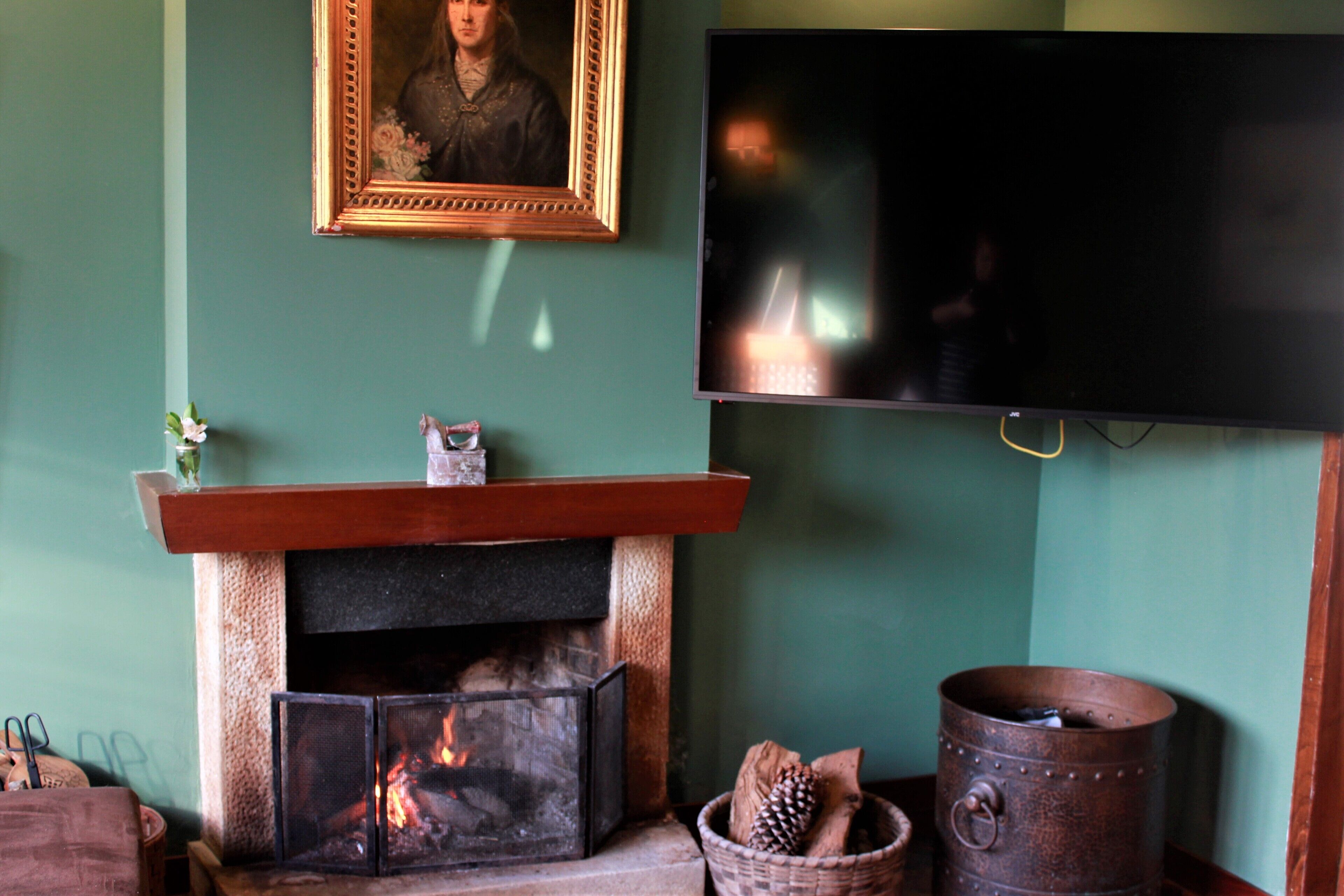A living room with a fireplace, a television mounted on the wall, and a framed picture above the fireplace.