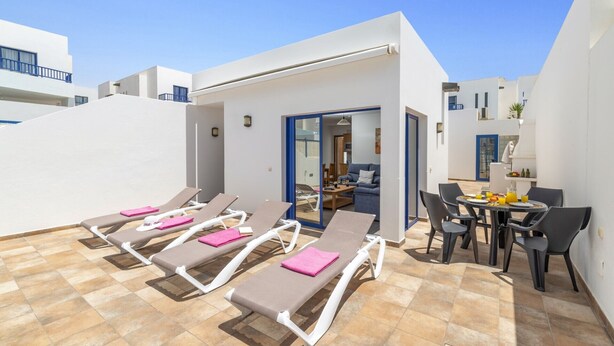 A rooftop terrace with sun loungers, a dining table with chairs, and a small kitchen area. - Villa Blanca by Villa Plus (Playa Blanca)
