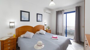 A bedroom with a double bed, two bedside tables, a nightstand, a window with curtains, and a ceiling light. - Villa Blanca by Villa Plus (Playa Blanca)