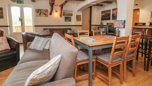 Un intérieur chaleureux avec une table en bois, des chaises et un canapé agrémenté de coussins.