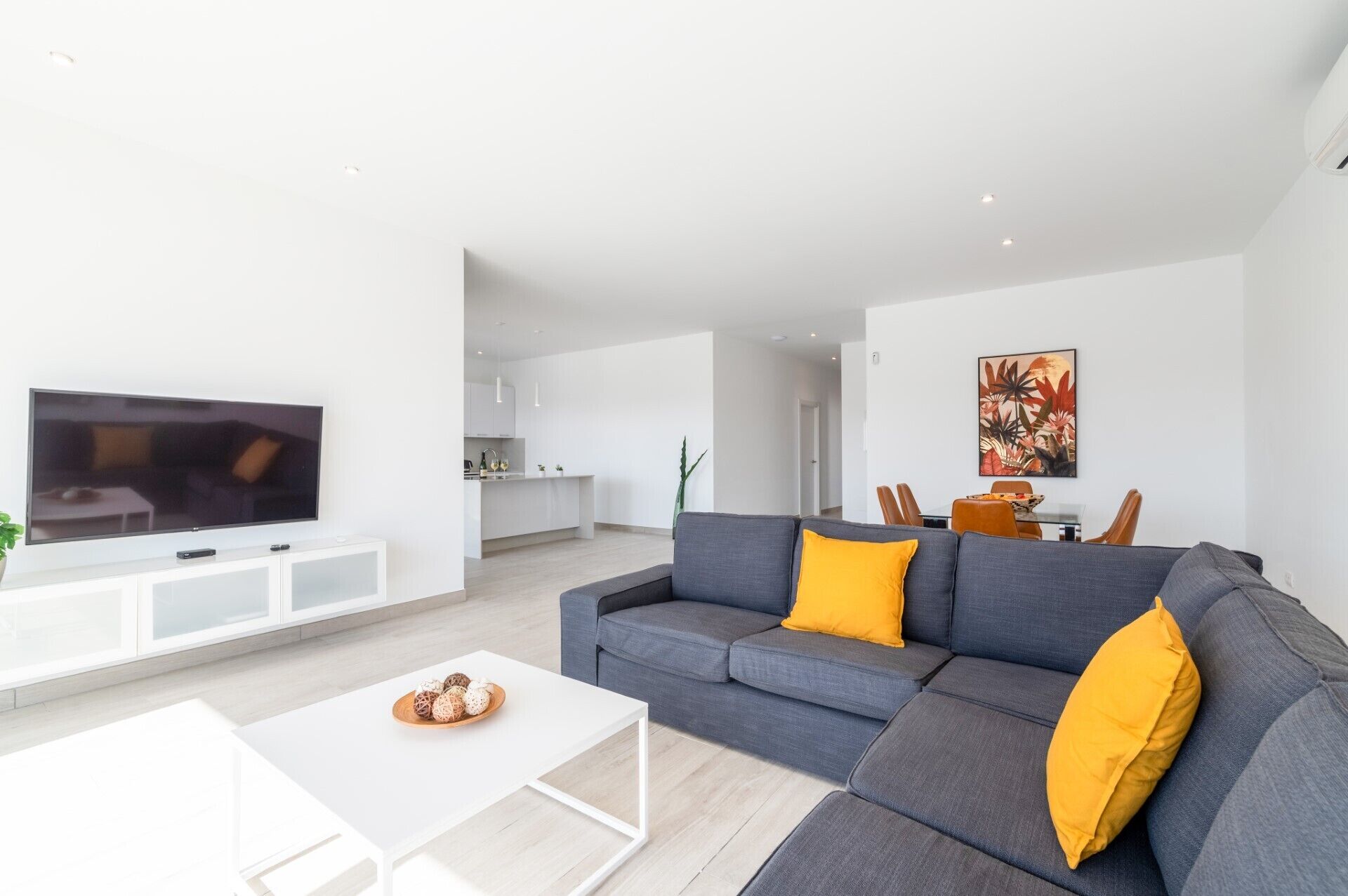 A modern living room with a grey sofa, white coffee table, and a flat-screen TV.