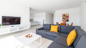 A modern living room with a grey sofa, white coffee table, and a flat-screen TV. - Villa Mifaya by Villa Plus (Playa Blanca)