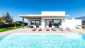 A modern house with a swimming pool, outdoor seating, and a well-maintained garden. - Villa Mifaya by Villa Plus (Playa Blanca)