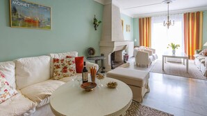 Ein Wohnzimmer mit einem weißen Sofa, einem runden Couchtisch, einem Kamin und einem Essbereich mit Tisch und Stühlen.