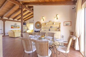 Un coin repas avec des chaises en osier, une table en verre et un buffet installé à l’arrière-plan.