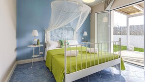 Une chambre à coucher avec un lit, une table de chevet, une lampe et une fenêtre donnant sur l’extérieur.