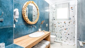 Ein modernes Badezimmer mit einem Holzlagerfläschchen, einem großen Spiegel und einer Dusche mit Glastür.