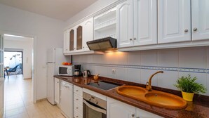 Una cucina moderna con mobili bianchi, un piano di lavoro in granito, un lavello doppio e un forno a microonde.