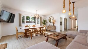Amplia sala de estar con un sofá grande, una mesa de centro de madera y un comedor con una mesa y sillas de madera.