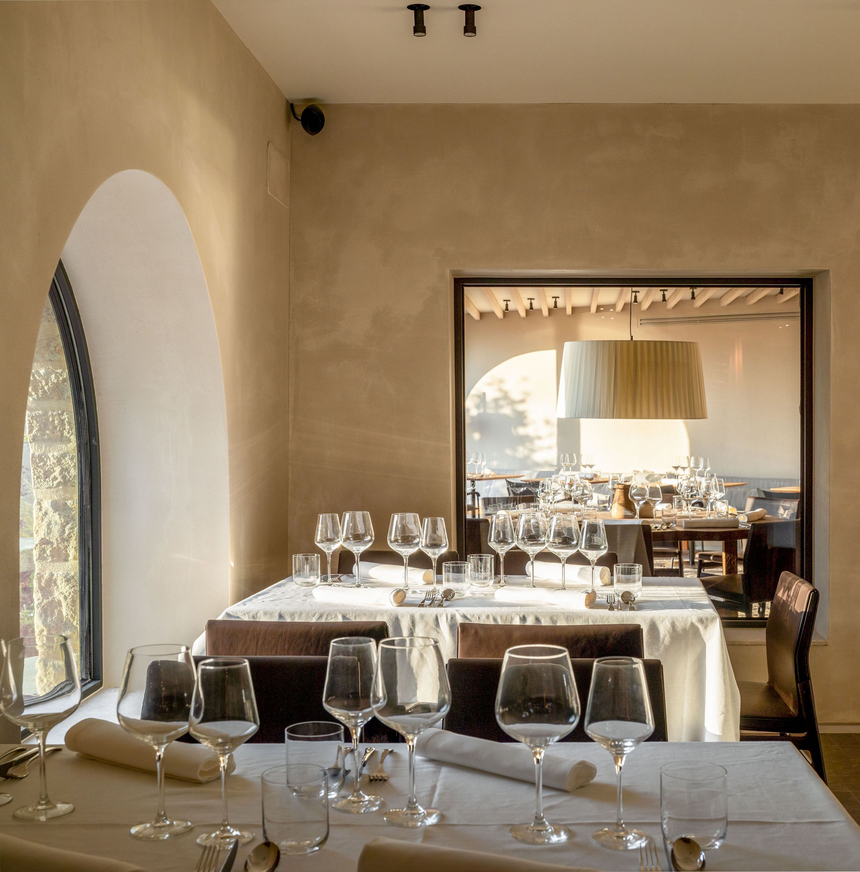 Un espace repas avec des tables dressées pour le repas, une grande fenêtre et une vue sur l’extérieur.