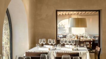 Un espace repas avec des tables dressées pour le repas, une grande fenêtre et une vue sur l’extérieur.