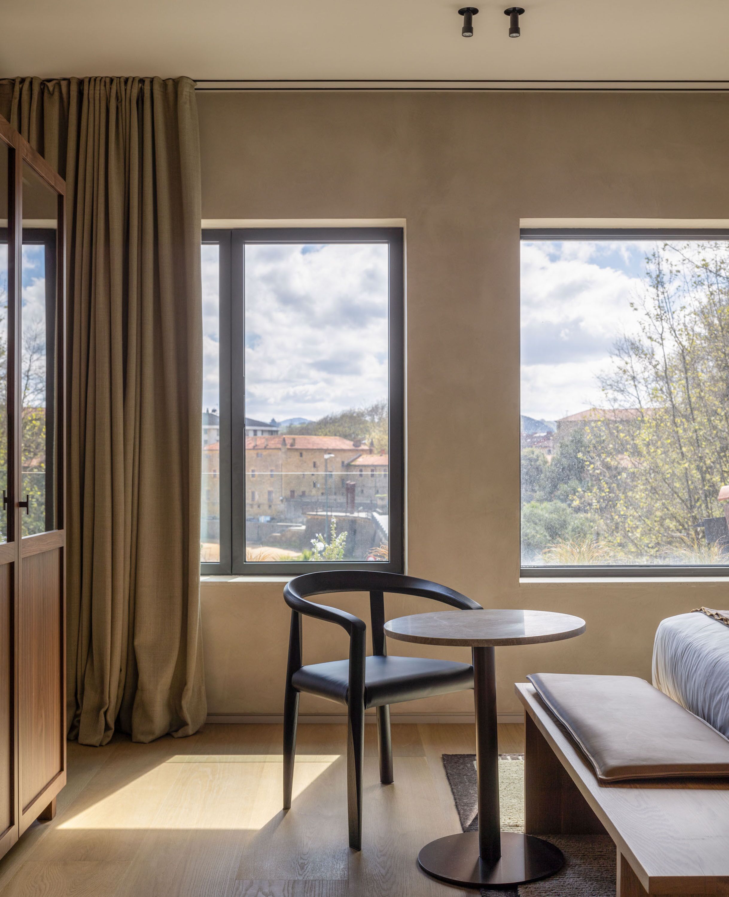 Ein Zimmer mit großem Fenster, einem Sessel, einem kleinen Tisch und einer Couch.