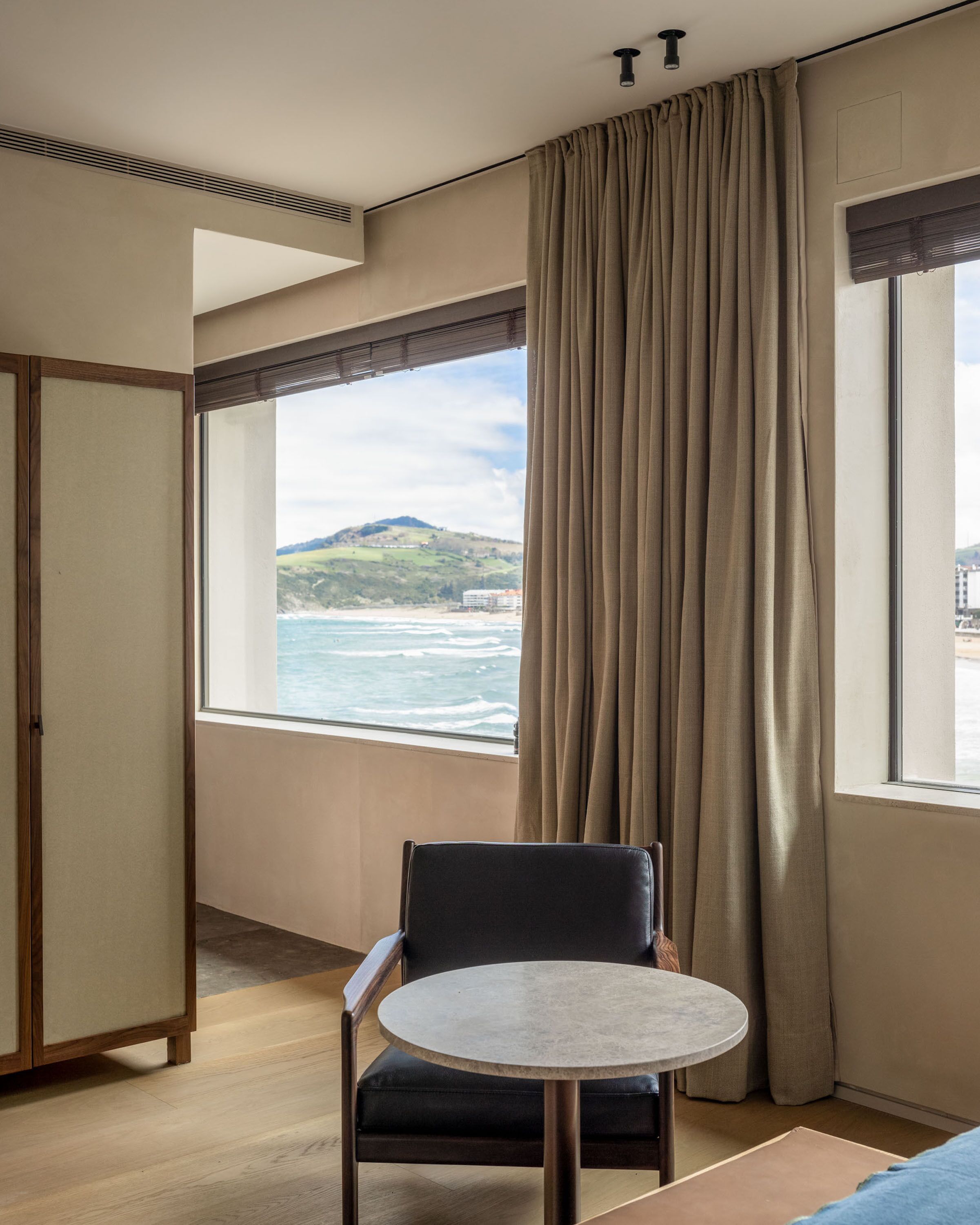 Une chambre d’hôtel avec vue sur l’océan, une table ronde, une chaise et une armoire.