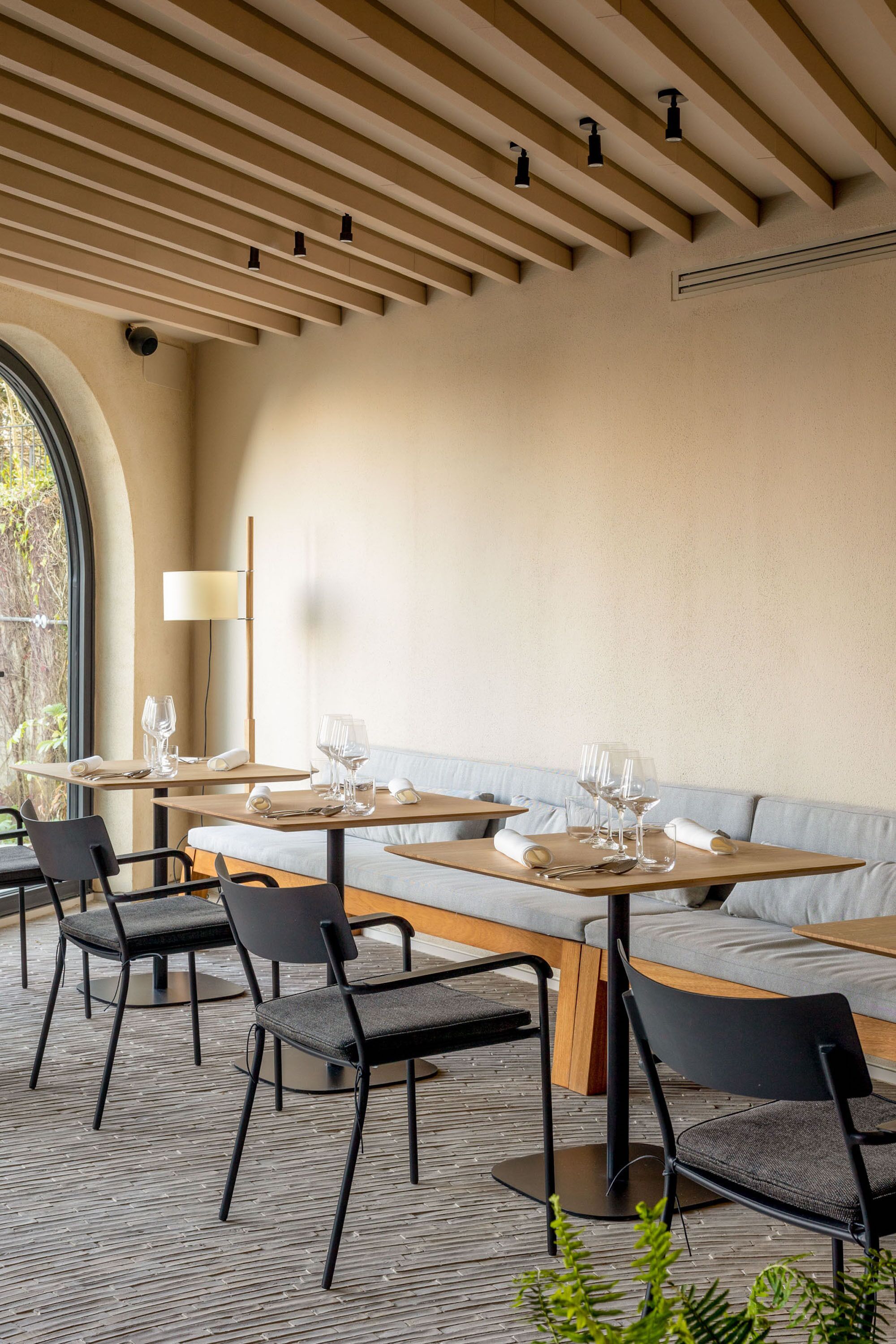 Un comedor moderno con mesas, sillas, un sofá y una lámpara.