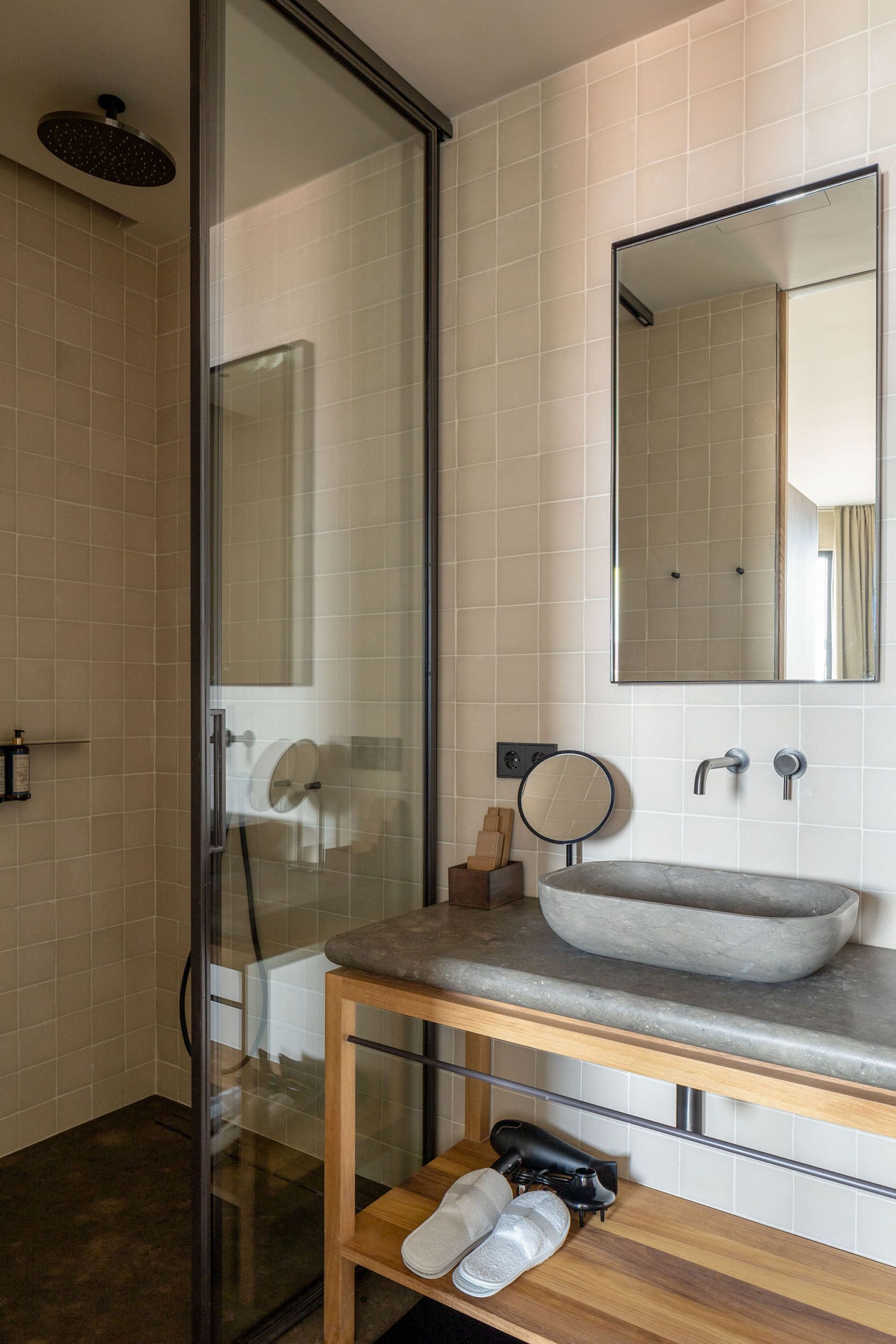 Un baño moderno con cabina de ducha de vidrio, un espejo grande, un lavabo sobre encimera y un mueble de tocador de madera.