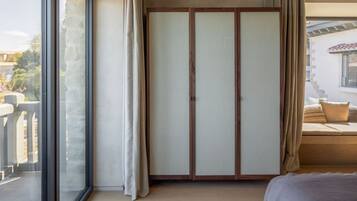 Un dormitorio con un amplio ventanal corredera, una cama, un armario de madera y vistas al exterior.