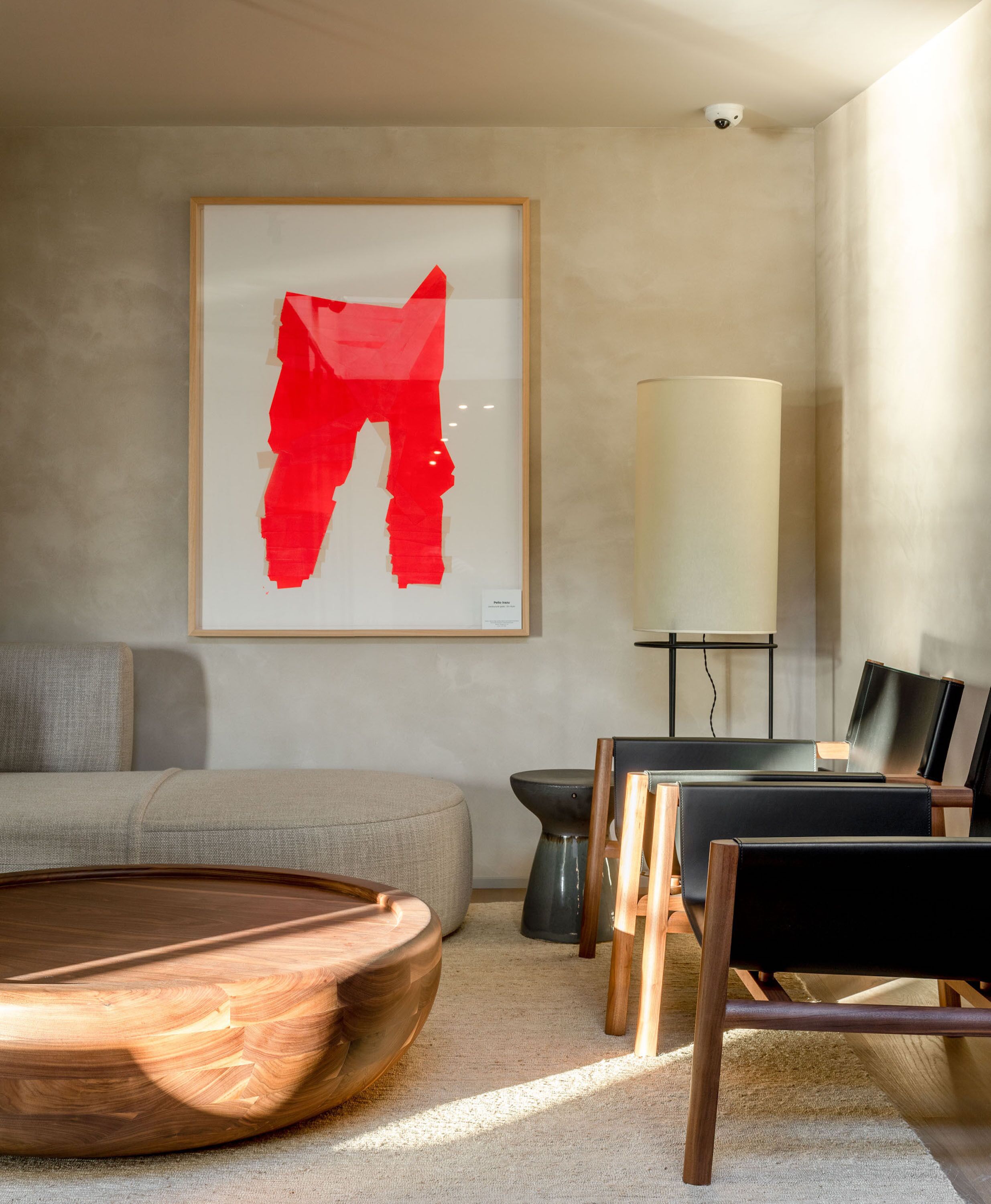 Una sala de estar moderna con un cuadro abstracto grande, una mesa de centro de madera, un sofá y una mesita de noche con una lámpara.