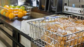 A kitchen area with a toaster and a basket of oranges.