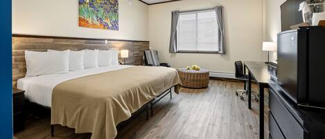 A hotel room with a bed, a desk, a television, and a painting on the wall.