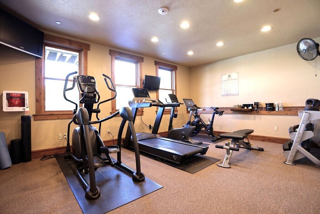 A gym with treadmills, elliptical machines, and a bench press.