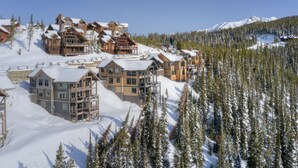 Ein schneebedecktes Chalet mit mehreren Gebäuden, Skiliften und einer Bergkulisse.