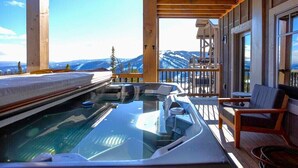 Ein Whirlpool auf einer Holzterrasse mit Blick auf die Berge.