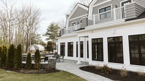 A two-story house with a covered patio area and a stone fireplace. - Grasshopper Inn (Ogunquit)