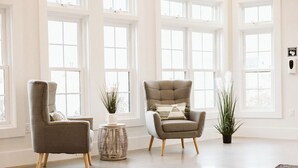 A spacious room with large windows, two armchairs, a small round table, and a potted plant. - Grasshopper Inn (Ogunquit)