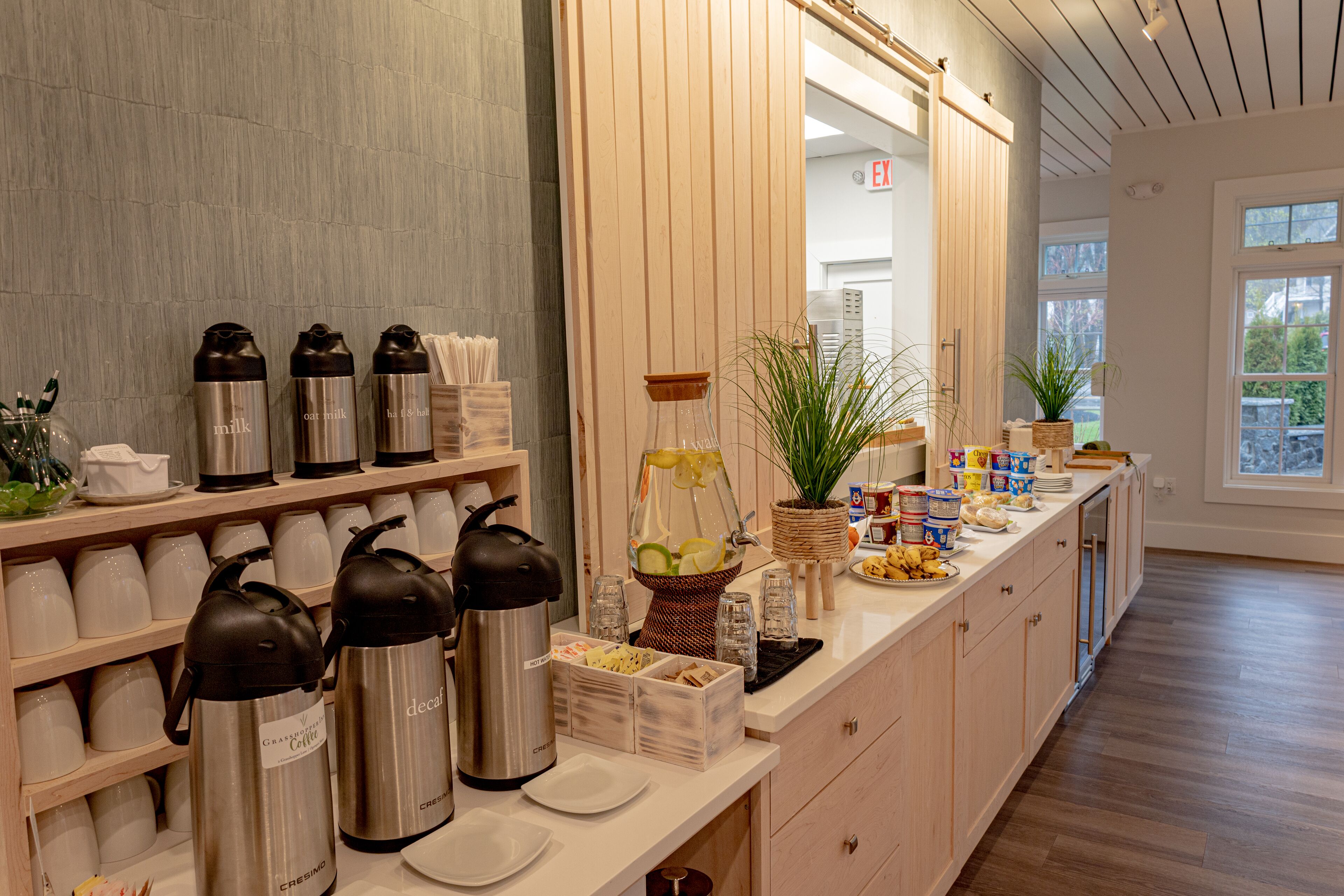 A breakfast bar with coffee makers, tea kettles, and a fruit bowl.