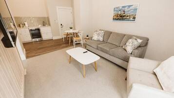 A compact living space with a kitchenette, a sofa, a coffee table, and a dining area.