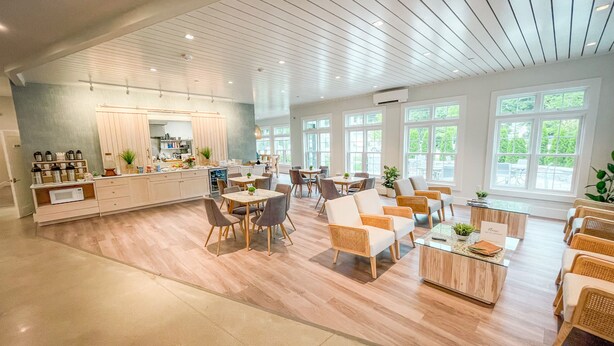 A spacious hotel lobby with a central dining area, multiple seating arrangements, and large windows providing natural light. - Grasshopper Inn (Ogunquit)