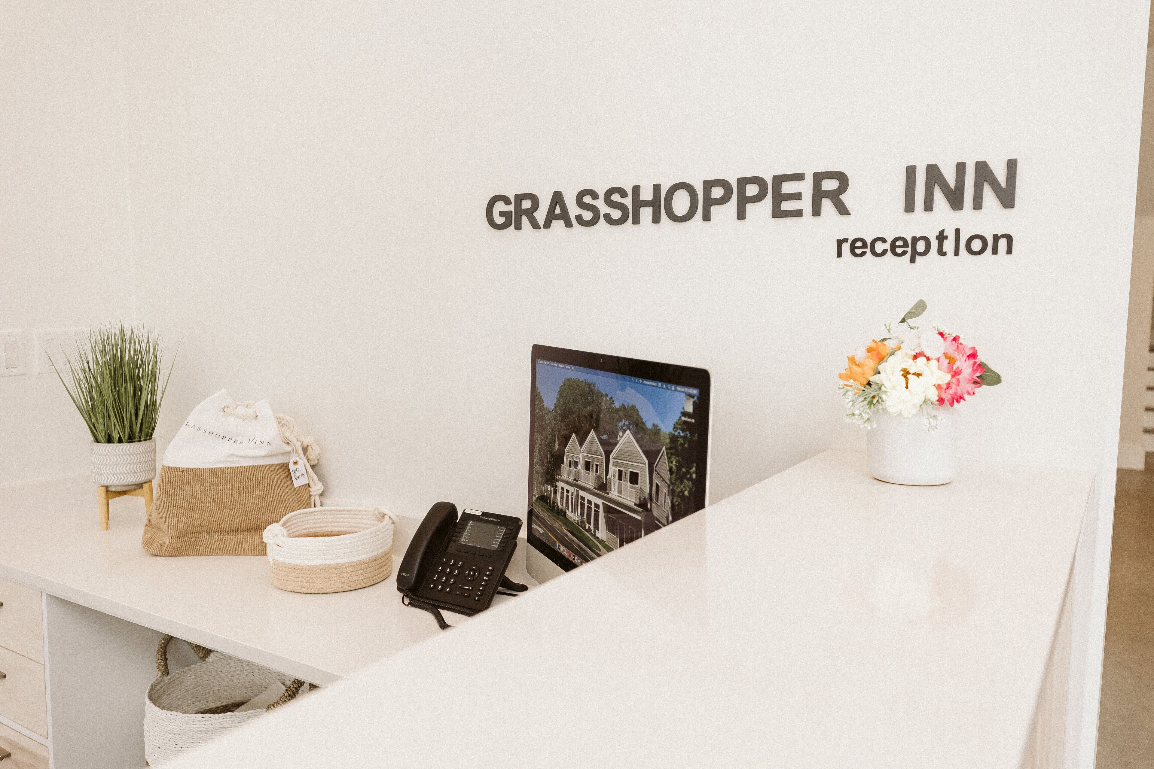 Eine Rezeption in der Grasshopper Inn mit einem Telefon, einem gerahmten Foto, einer Blumenvase und einer Pflanze.