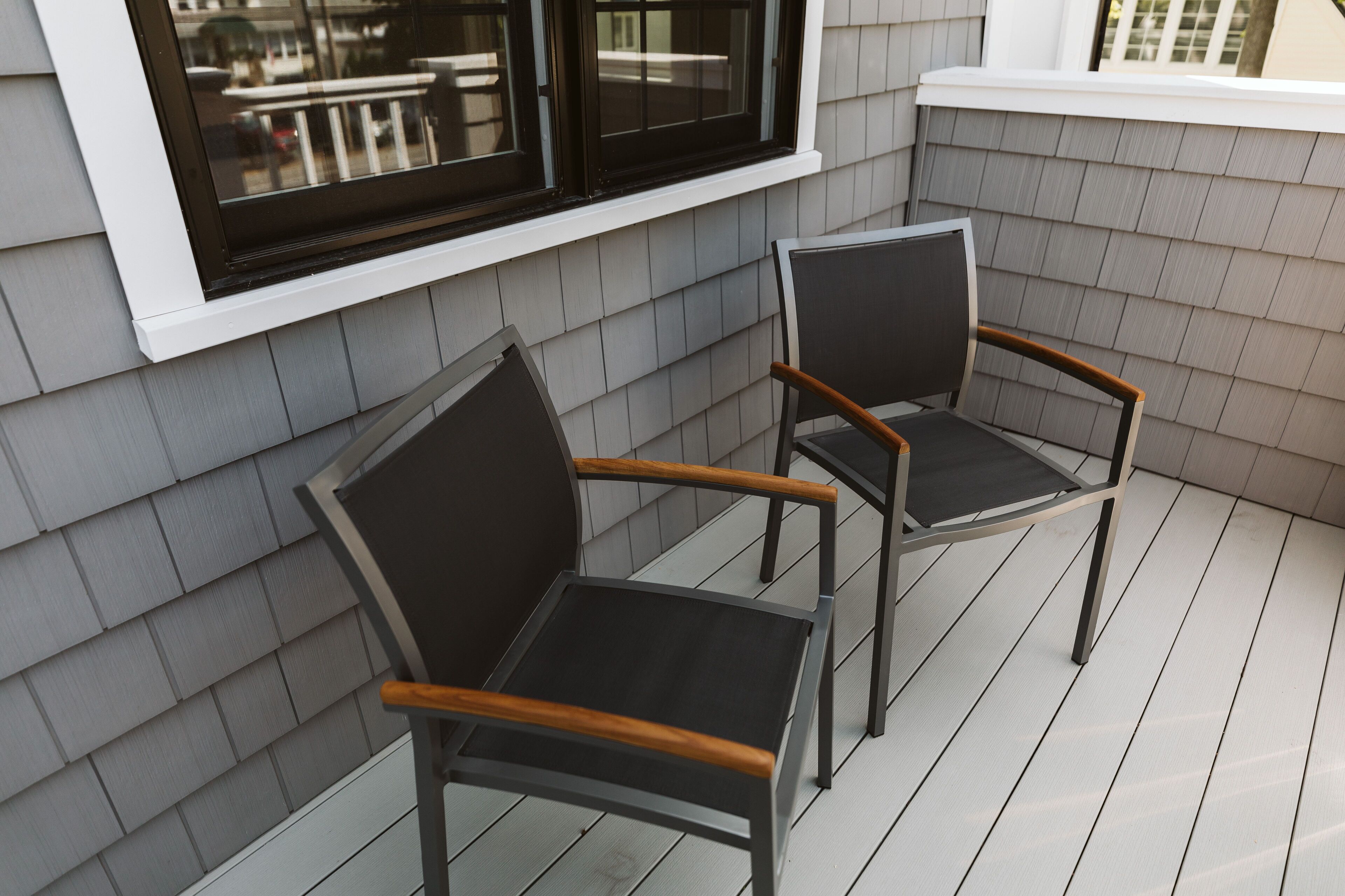 Two chairs on a wooden deck with a window above them.