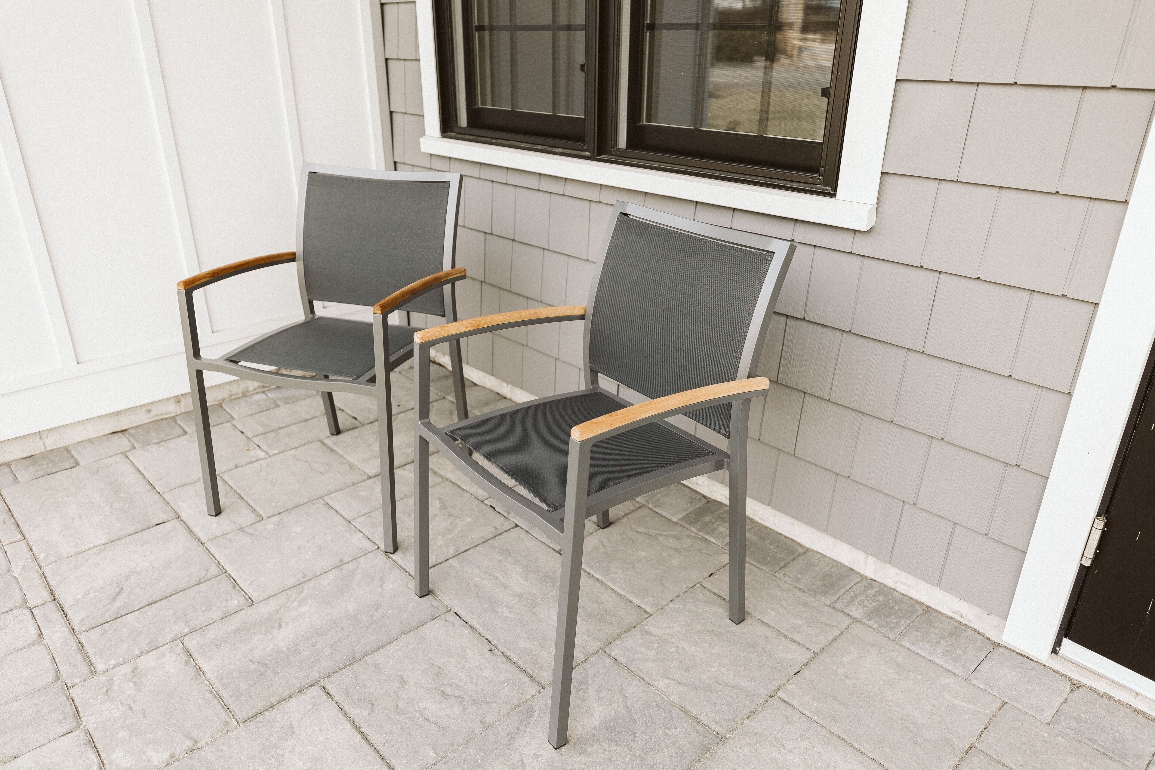 Two chairs with metal frames and wooden armrests, positioned on a tiled patio area.