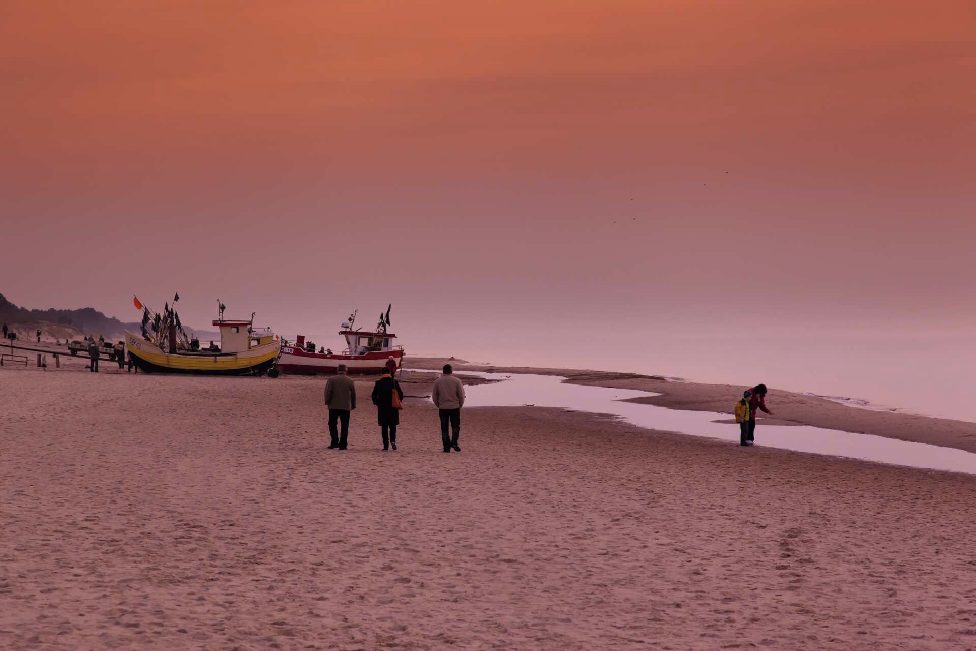 A beach with a boat and people.