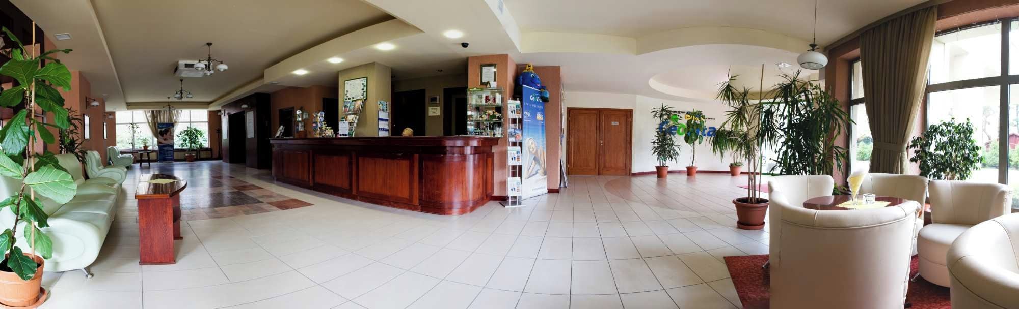 Rebedor d'hotel amb taulell de recepció, zona d'estar i plantes en testos.