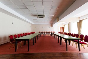 Ein Konferenzraum mit einem langen Tisch, roten Stühlen, weißen Wänden und einem roten Teppich.
