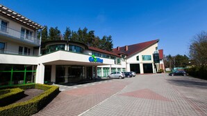 En byggnad med en skylt med texten ”Coca-Cola”, en överbyggd entré och en parkeringsplats med bilar.