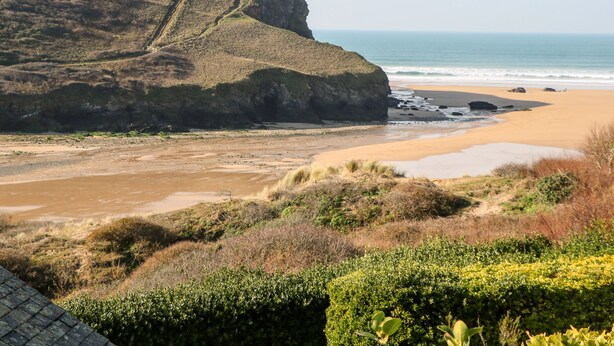 A coastal landscape with a sandy beach, a cliff, and a view of the ocean. - The Bright House (Wadebridge)