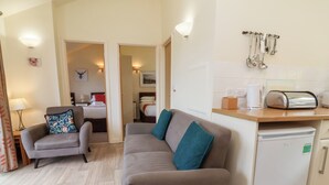A compact living space with a sofa, armchair, and a small kitchenette. - 11 Manleigh Park (Ilfracombe)